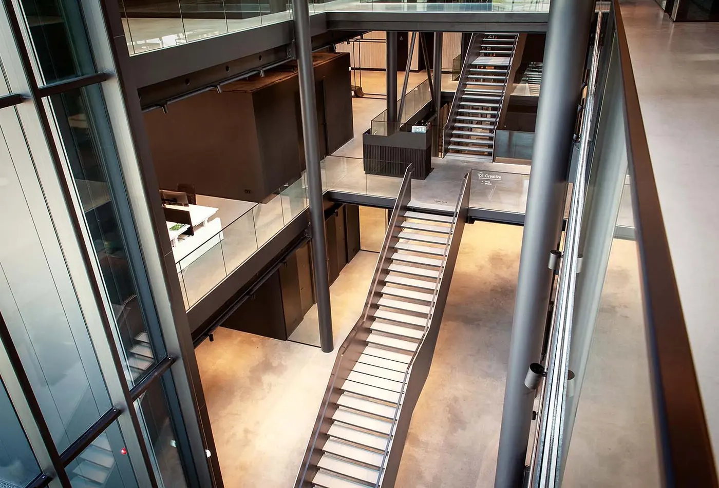 Stalen hoofdtrap met glasbalustrade in het kantoorpand van Rev'it in Oss