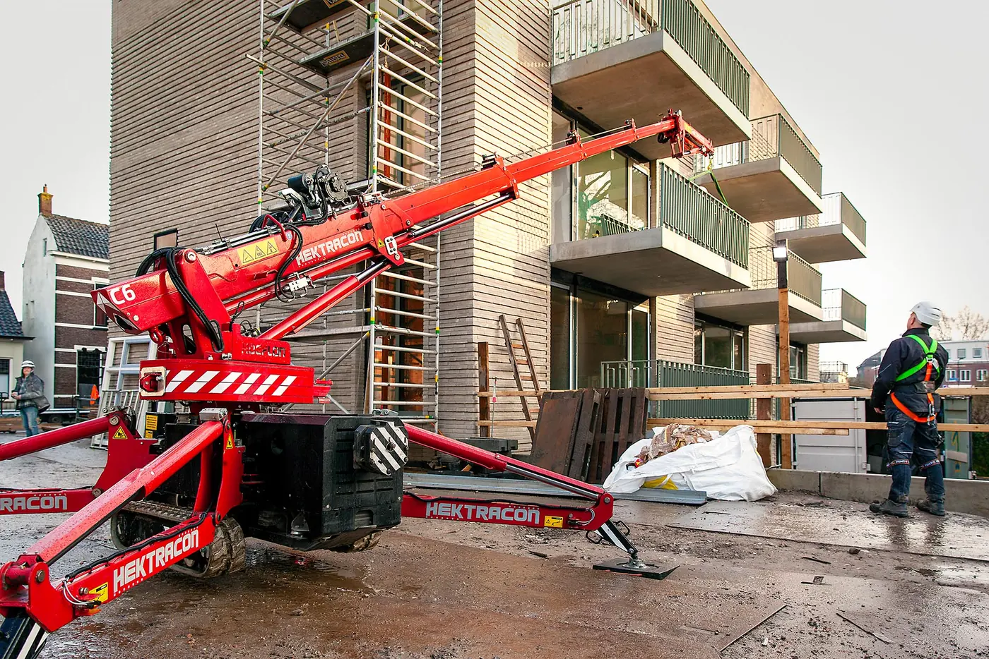 Monteur van Hektracon bij de rode rupskraan tijdens de montage van balkons