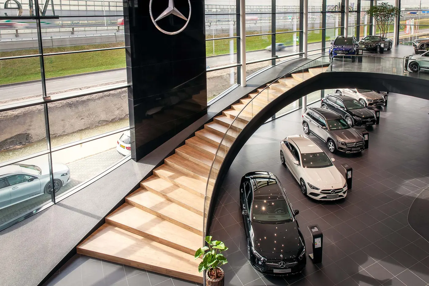 Gebogen stalen hoofdtrap met eikenhouten treden in de Van Mossel-showroom in Rotterdam